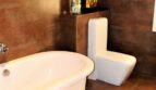 Luxusbadezimmer mit freistehender Badewanne, modernem WC und eleganten Kupfer-Wandfliesen in Marratxí-Villa