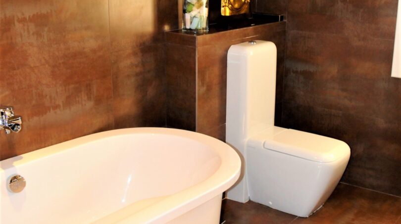 Luxusbadezimmer mit freistehender Badewanne, modernem WC und eleganten Kupfer-Wandfliesen in Marratxí-Villa