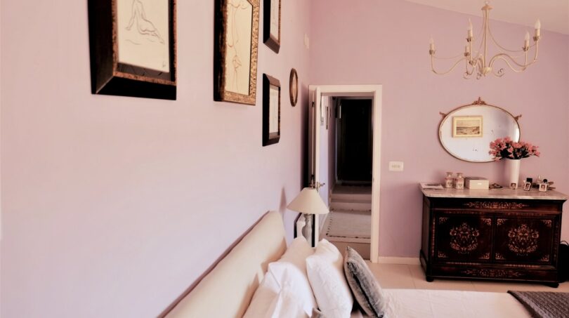 Elegantes Schlafzimmer mit Lila-Wänden, antikem Kommode, Kronleuchter und Kunstwerken in Villa Marratxí