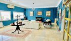 Elegantes Wohnzimmer mit blauem Wanddesign, Marmorboden, weißer Couch und Gemälden in Marratxí-Villa.