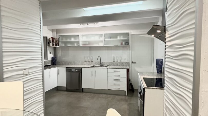 Moderne weiße Küche mit Granitarbeitsplatten, Geschirrspüler und Skylight in exklusiver Villa Marratxí