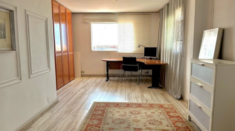 Helles Arbeitszimmer mit Holzparkett, Einbauschrank, Schreibtisch und großem Fenster in Villa Marratxí