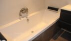 Modernes weißes Einbaubad mit Chromarmatur und dunklen Akzenten in exklusiver Villa Marratxí