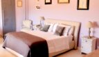 Elegantes Schlafzimmer mit rosa Wänden, Kronleuchtern, Doppelbett und Kunstwerken in Villa Marratxí