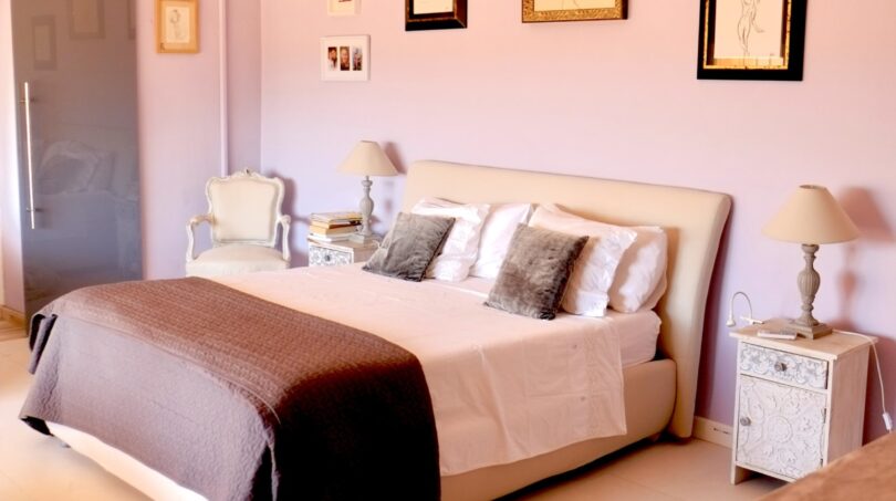 Elegantes Schlafzimmer mit rosa Wänden, Kronleuchtern, Doppelbett und Kunstwerken in Villa Marratxí