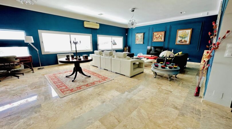 Elegantes Wohnzimmer mit Marmorboden, blauen Wänden, weißen Sofas und Gemälden in Villa Marratxí