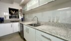 Moderne Küche mit Granitarbeitsplatte, weißen Hochglanzschränken und Edelstahlspüle in Luxusvilla Marratxí
