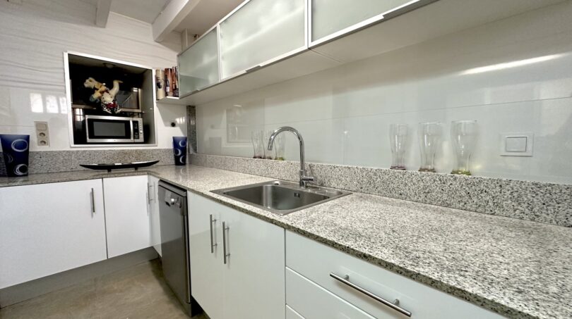 Moderne Küche mit Granitarbeitsplatte, weißen Hochglanzschränken und Edelstahlspüle in Luxusvilla Marratxí