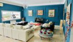 Elegantes Wohnzimmer mit petrolblauen Wänden, weißen Ledersofas, Marmorboden und Kunstgemälden in Marratxí.
