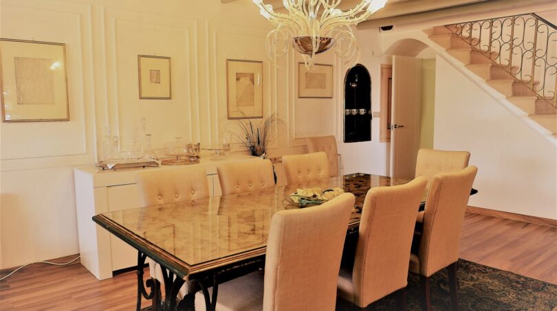 Elegantes Esszimmer mit Glasstisch, Kronleuchter und Treppe in Luxusvilla Marratxí