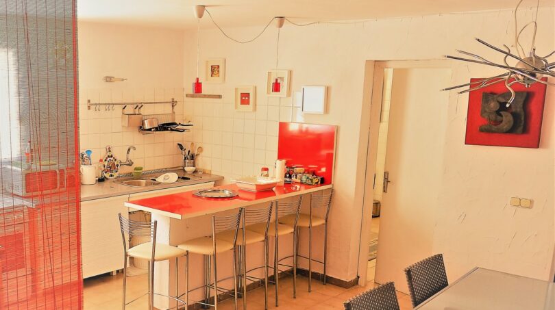 Moderne Küche mit roter Kücheninsel und Barhockern in exklusiver Villa in Marratxí