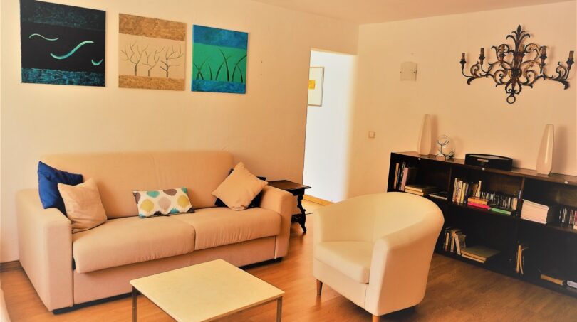 Helles Wohnzimmer mit Sofa, Sessel, Bücherregal und dekorativen Kunstwerken in Marratxí