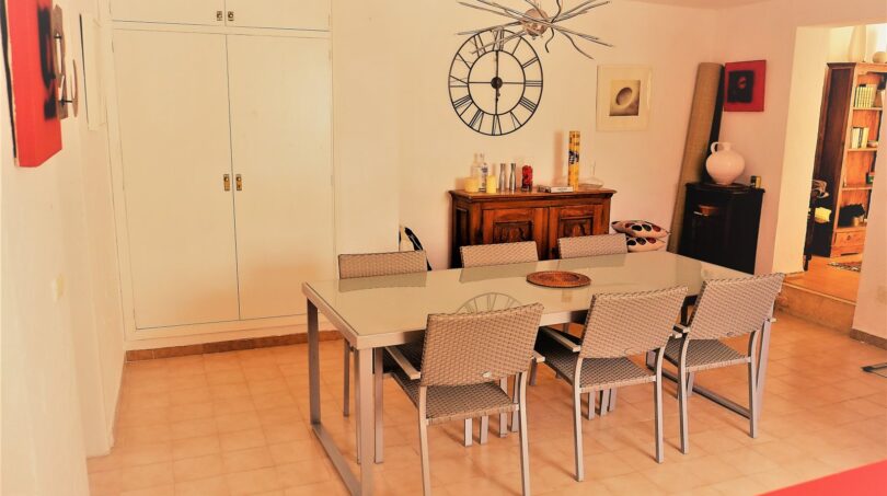 Elegantes Esszimmer mit modernem Glastisch, Designerstühlen und dekorativer Wanduhr in Marratxí-Villa