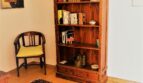 Wohnzimmer mit Holzbücherregal, antikem Stuhl, orientalischem Teppich und Gemälden in mallorquinischer Villa.