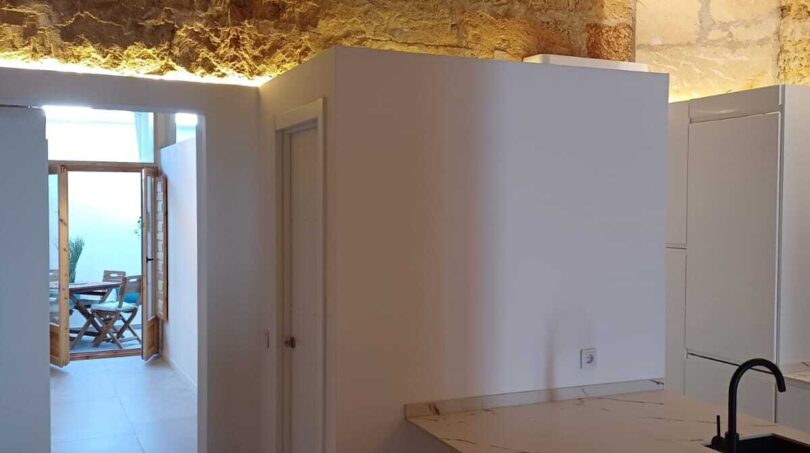 Moderne Küche mit Marmortresen, Natursteinwand und Holzbalkendecke in Erdgeschosswohnung Palma