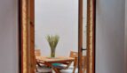Blick durch geöffnete Holzflügeltür auf überdachte Terrasse mit Holztisch und Stühlen, Erdgeschosswohnung Palma
