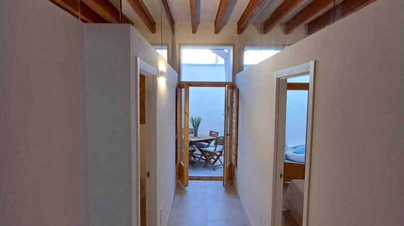 Heller Flur mit Holzbalkendecke und Glasgeländer, führt zu sonniger Terrasse mit Esstisch, Palma de Mallorca