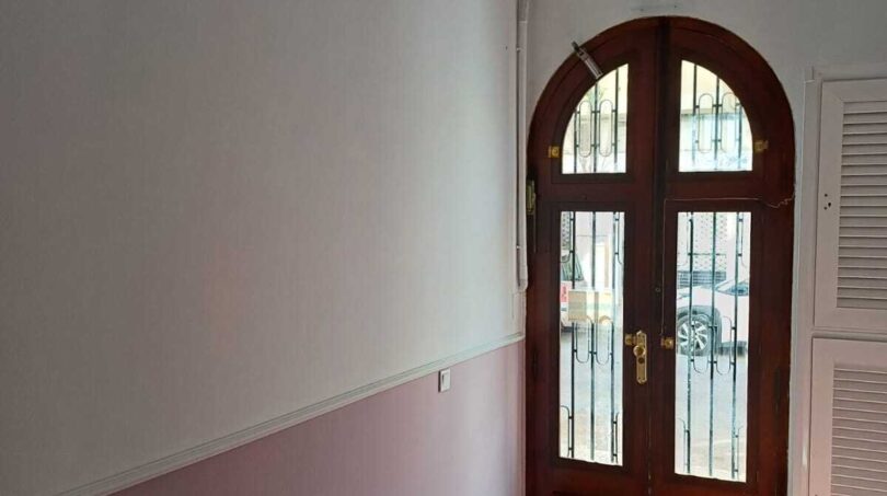 Eingangsbereich der Erdgeschosswohnung in Palma mit elegantem Rundbogenportal aus Holz und Terrakottaboden.