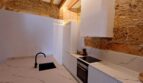 Moderne weiße Küche mit Marmorarbeitsplatte, schwarzem Armatur und Natursteinwand in Erdgeschosswohnung Palma