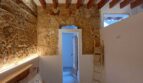 Schlafzimmer mit Natursteinwand, Holzbalkendecke und Blumenbettwäsche in Erdgeschosswohnung Palma