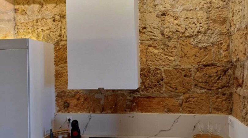 Moderne weiße Küche mit Marmorarbeitsplatte und original Natursteinwand in Erdgeschosswohnung in Palma