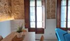 Wohnzimmer mit Natursteinwand, Holzbalkendecke, blauem Sofa und Esstisch in Erdgeschosswohnung, Palma de Mallorca