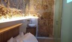 Schlafzimmer mit Natursteinwand, Holzbalkendecke, Doppelbett und integriertem Waschbecken in Palma