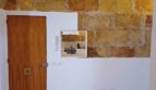 Küche mit rustikaler Natursteinwand, Holzbalkendecke, weißer Marmorarbeitsplatte und Holztür in Palma