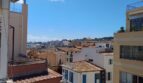 Blick vom Balkon über die Dächer von Palma de Mallorca mit blauem Himmel und Meerblick im Hintergrund