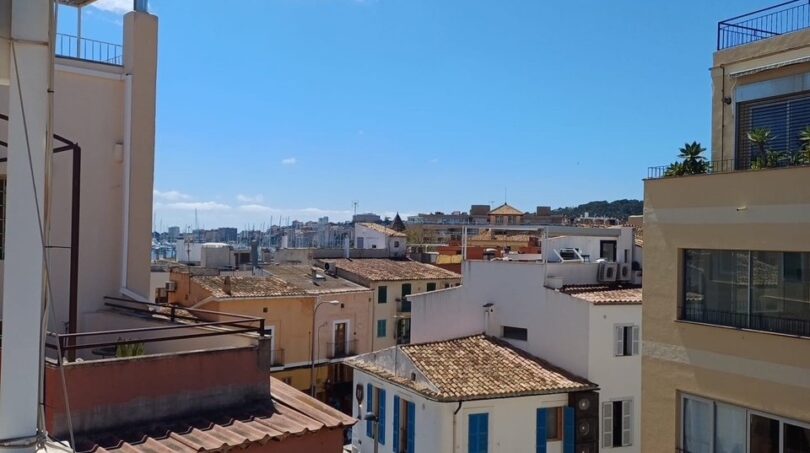 Blick vom Balkon über die Dächer von Palma de Mallorca mit blauem Himmel und Meerblick im Hintergrund