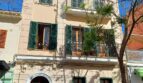 Außenansicht eines gepflegten Altbaus in Palma mit grünen Fensterläden, Balkonen und elegantem Rundbogeneingang.