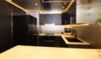 Moderne Luxusküche mit schwarzen Hochglanzfronten, Marmor-Arbeitsflächen und stimmungsvoller LED-Beleuchtung