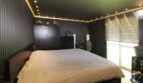 Modernes Schlafzimmer mit Doppelbett, dunklen Wänden, indirekter LED-Beleuchtung und großer Fensterfont in Palma-Duplex