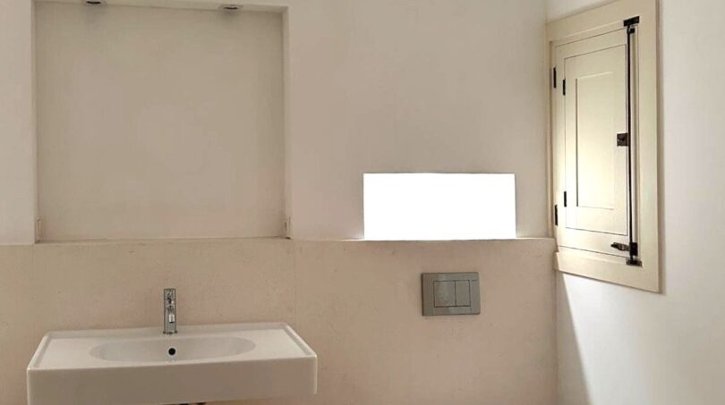Modernes Badezimmer mit wandmontierten WC und Waschbecken, Mikrozementverkleidung und Fensterläden in Palma de Mallorca