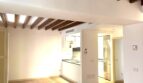 Helles Wohnzimmer mit Holzbalkendecke und offener Küche in renovierter Wohnung in Palma de Mallorca