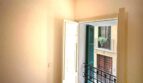 Helles Zimmer mit Balkon und Blick auf mediterrane Altbaufassade mit grünen Fensterläden in Palma