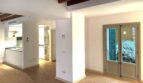 Renoviertes Wohnzimmer mit Holzbalkendecke, offenem Küchenbereich und Balkontür in Palma de Mallorca