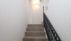 Escalera elegante con escalones de piedra natural, barandilla de hierro forjado e iluminación de pared en el ático Paseo del Borne