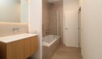 Baño moderno con bañera empotrada, ducha de lluvia y elegante tocador de madera en el ático Paseo del Borne