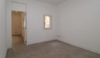 Dormitorio luminoso y vacío con piso de baldosas, pequeña ventana y paso al pasillo en el ático Born Palma