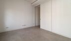 Dormitorio vacío con piso de baldosas gris, paredes blancas y puerta corrediza elegante en el ático Paseo del Borne