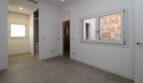 Dormitorio vacío con armario empotrado, luz natural y vista del muro de piedra histórico en el ático Borne Palma