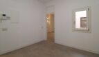 Sala luminosa y vacía con pisos de baldosas, paso al pasillo y pequeña ventana en el ático Born Palma
