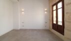 Espacio de estar vacío con apliques de pared, pared de piedra natural y ventanas de madera en el ático maisonette, Paseo del Borne, Palma