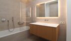 Baño moderno con bañera, tocador de madera flotante y espejo iluminado en el ático Palma