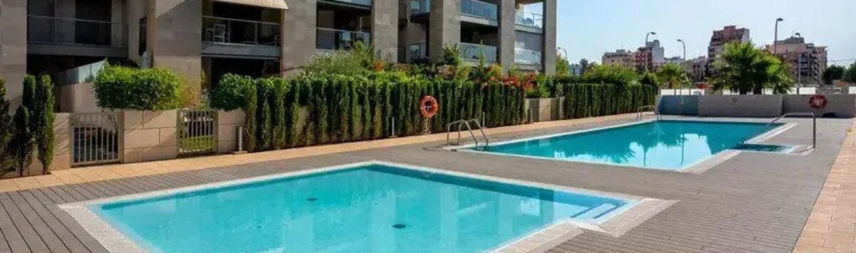 Piscina comunitaria con terraza de madera y complejo de apartamentos moderno en Palma de Mallorca