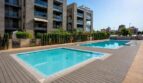 Piscina comunitaria con terraza de madera y complejo de apartamentos moderno en Palma de Mallorca