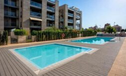 Gemeinschaftspool mit Holzterrasse und modernem Apartmentkomplex in Palma de Mallorca