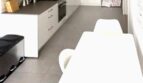 Cocina blanca moderna con isla de cocina, frigorífico de acero inoxidable y zona de comedor adyacente en Palma de Mallorca.