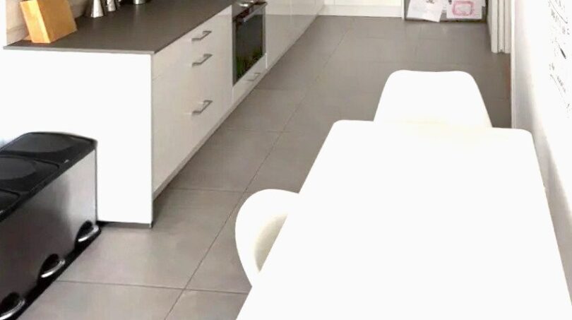 Cocina blanca moderna con isla de cocina, frigorífico de acero inoxidable y zona de comedor adyacente en Palma de Mallorca.